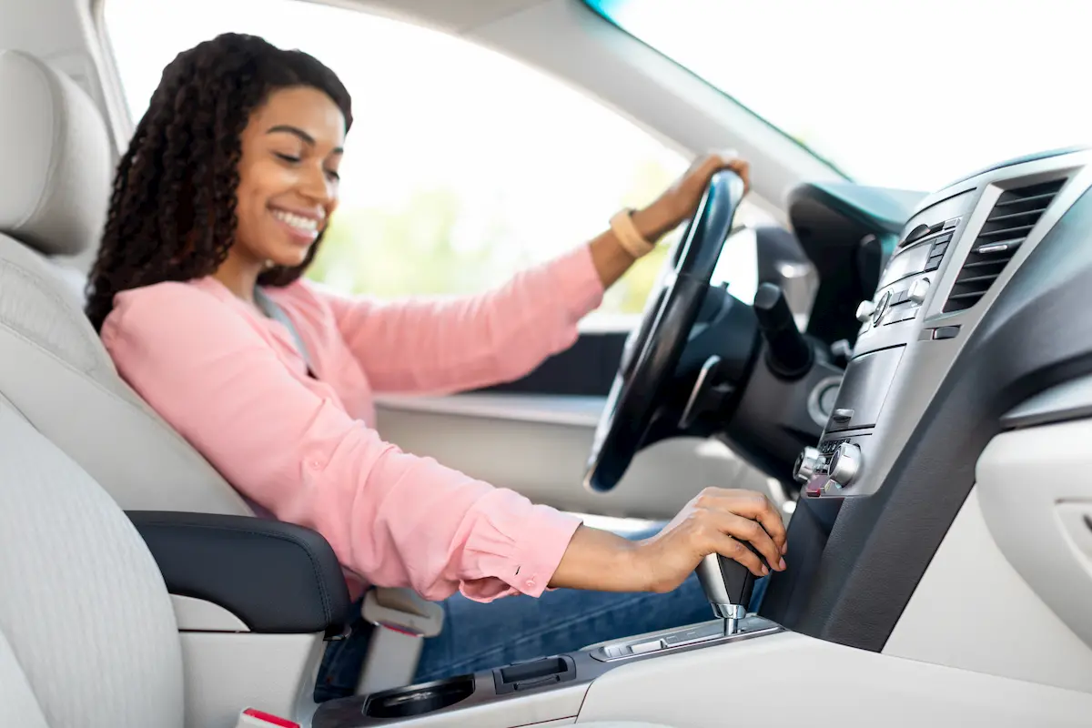 mujer sonríe mientras conduce un coche automático